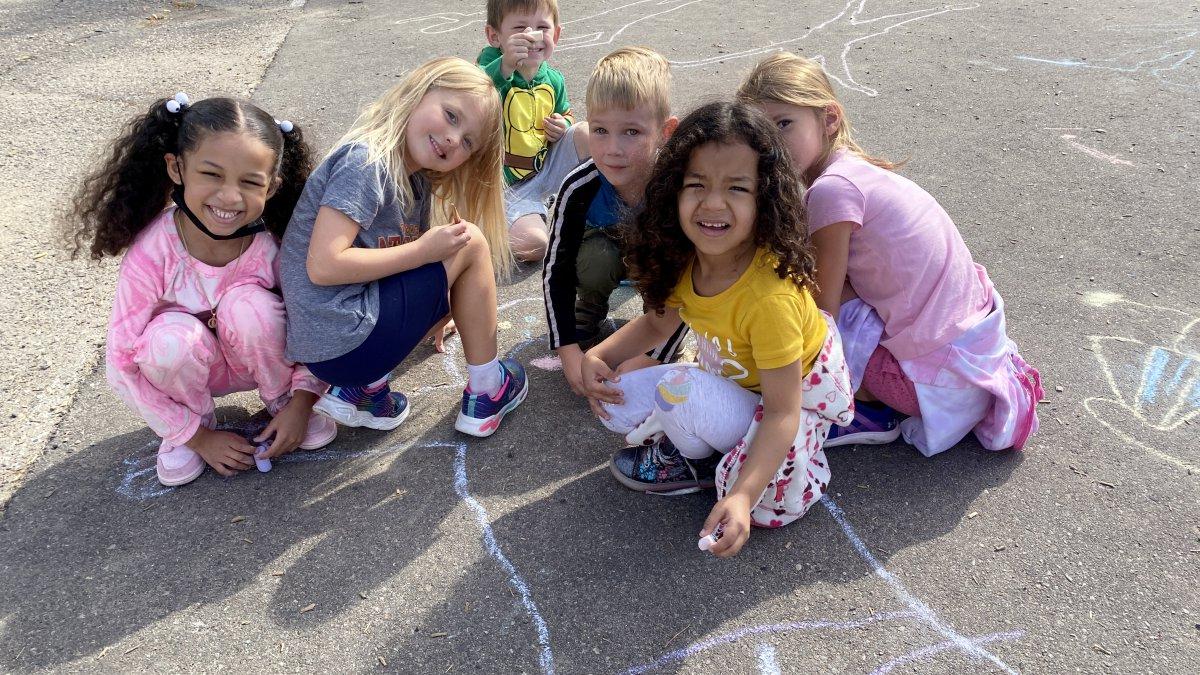 students drawing on pavement with chalk